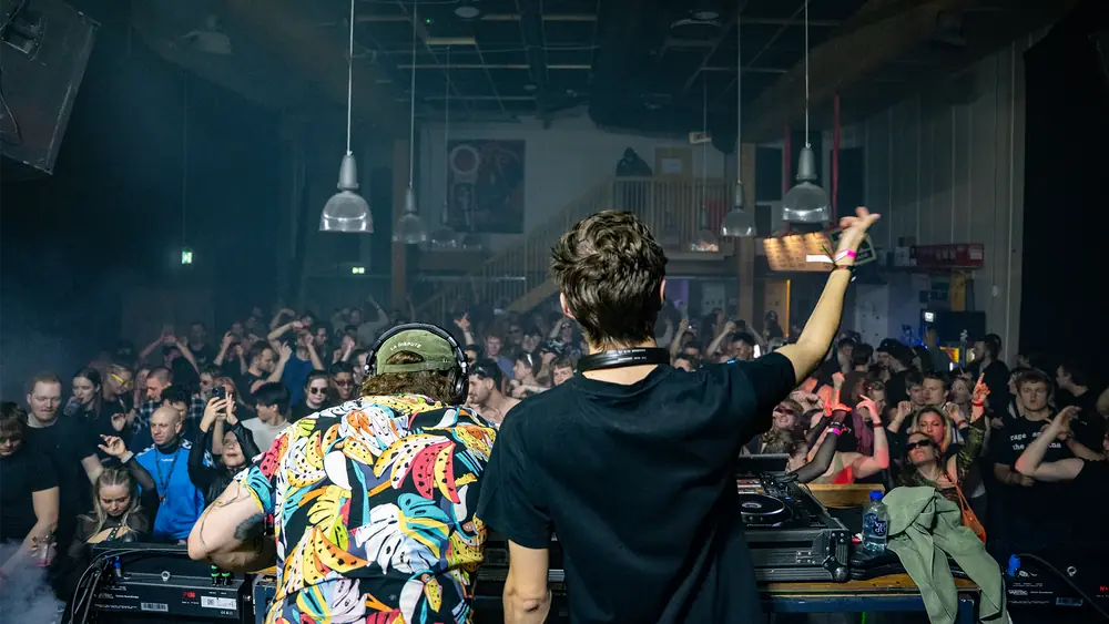 UNNØUNCED raising an arm from the DJ booth